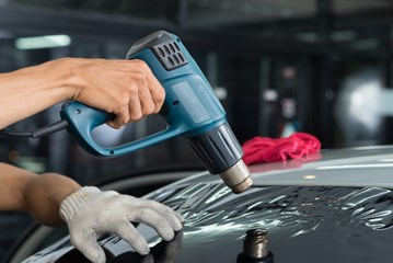 A heat gun being used on a car