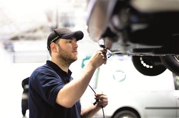 A Volkswagen Technician examining a vehicle.