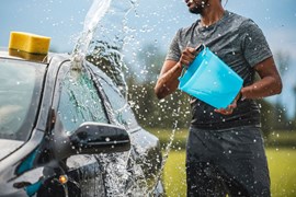 A car being cleaned with a bucket of water