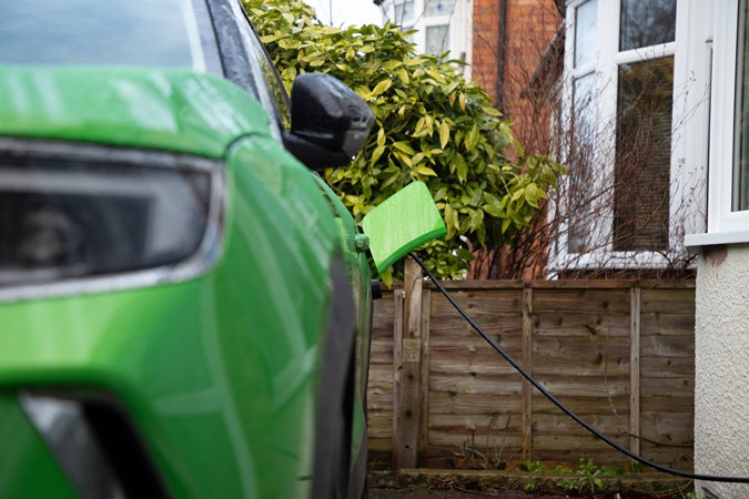 Electric car charger for home: Vauxhall Mokka Electric parked outside red-brick terraced house with cable plugged in