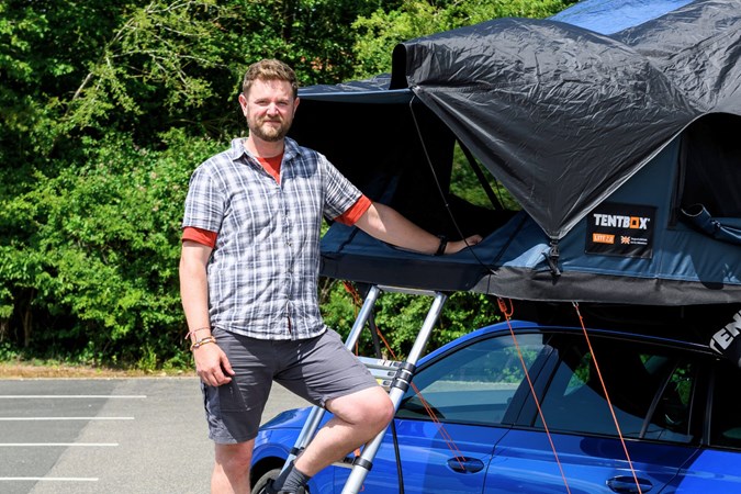 Adam Binnie posing next to a roof tent