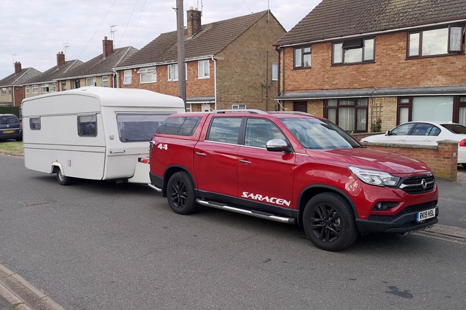 A red 2019 Ssangyong Musso with a caravan, on the road, photograph by Luke Neal