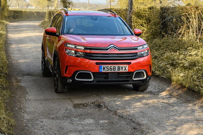 How to claim for pothole damage in the UK - red Citroen car next to large pothole