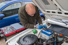 Bonnet open with battery in clear view, tools laid out on the wing or scuttle panel Alt text: Open bonnet with car battery visible and tools ready for replacement - how to change a car battery