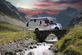 Campervan with leisure batteries driving over a bridge in the mountains