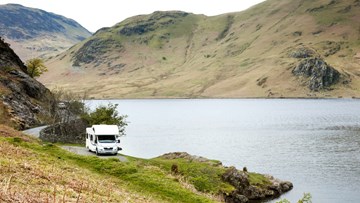 Campervan with leisure batteries driving down a road in the UK mountains