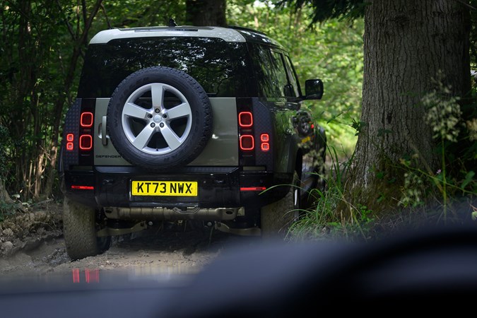 How to drive off-road: Land Rover Defender, rear three quarter driving, through mud and ruts, close up, green paint