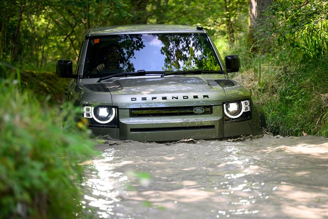 How to drive off-road: Land Rover Defender, front three quarter driving, through deep water, close up, green paint