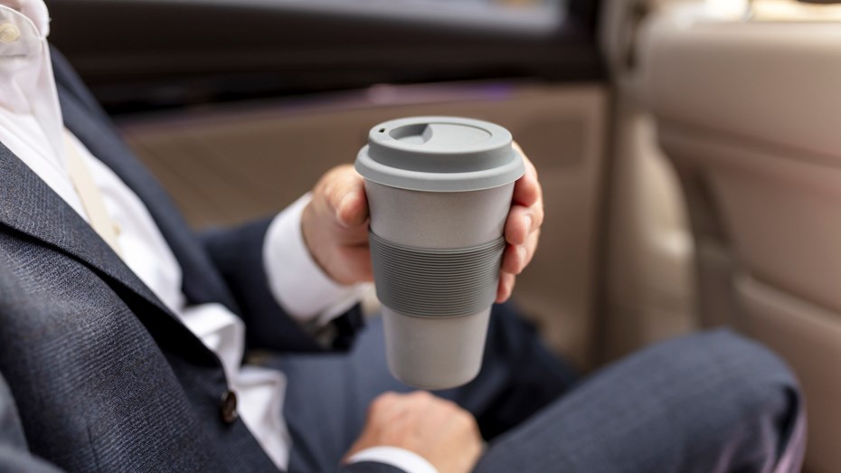 Man in a suit holding a travel mug