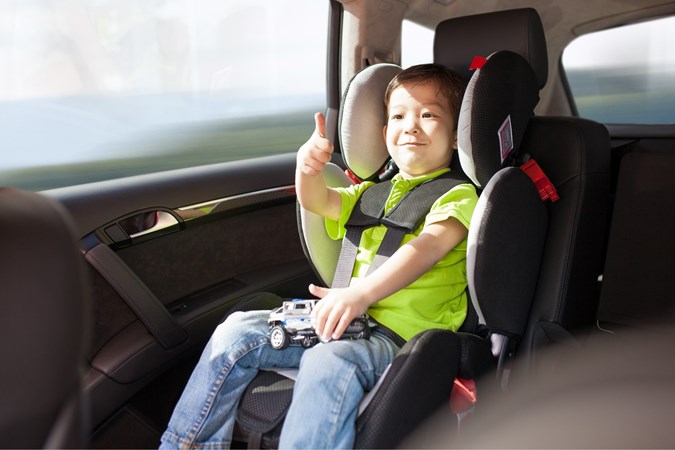 Child thumbs up in car seat