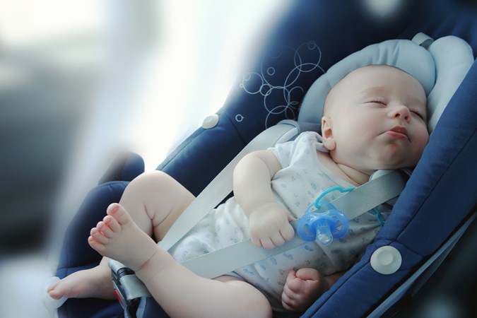 Very young baby asleep in baby car seat
