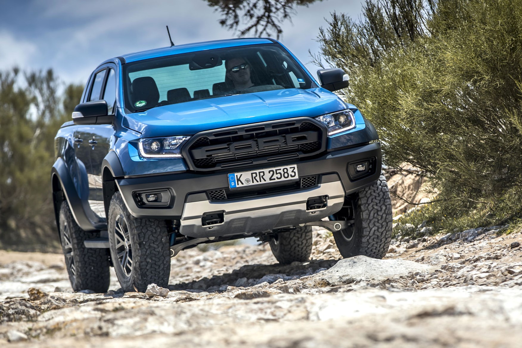 Ford Ranger Raptor high performance pickup truck - Performance Blue, front view, on rocks