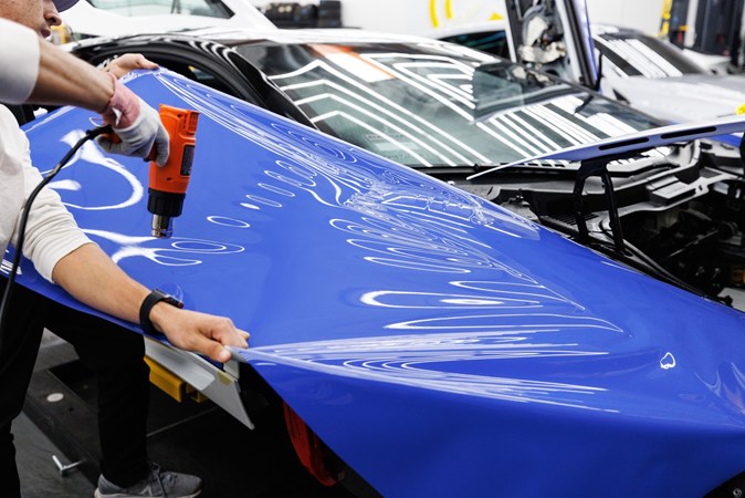 Purple car wrap being applied to the side panel of a car