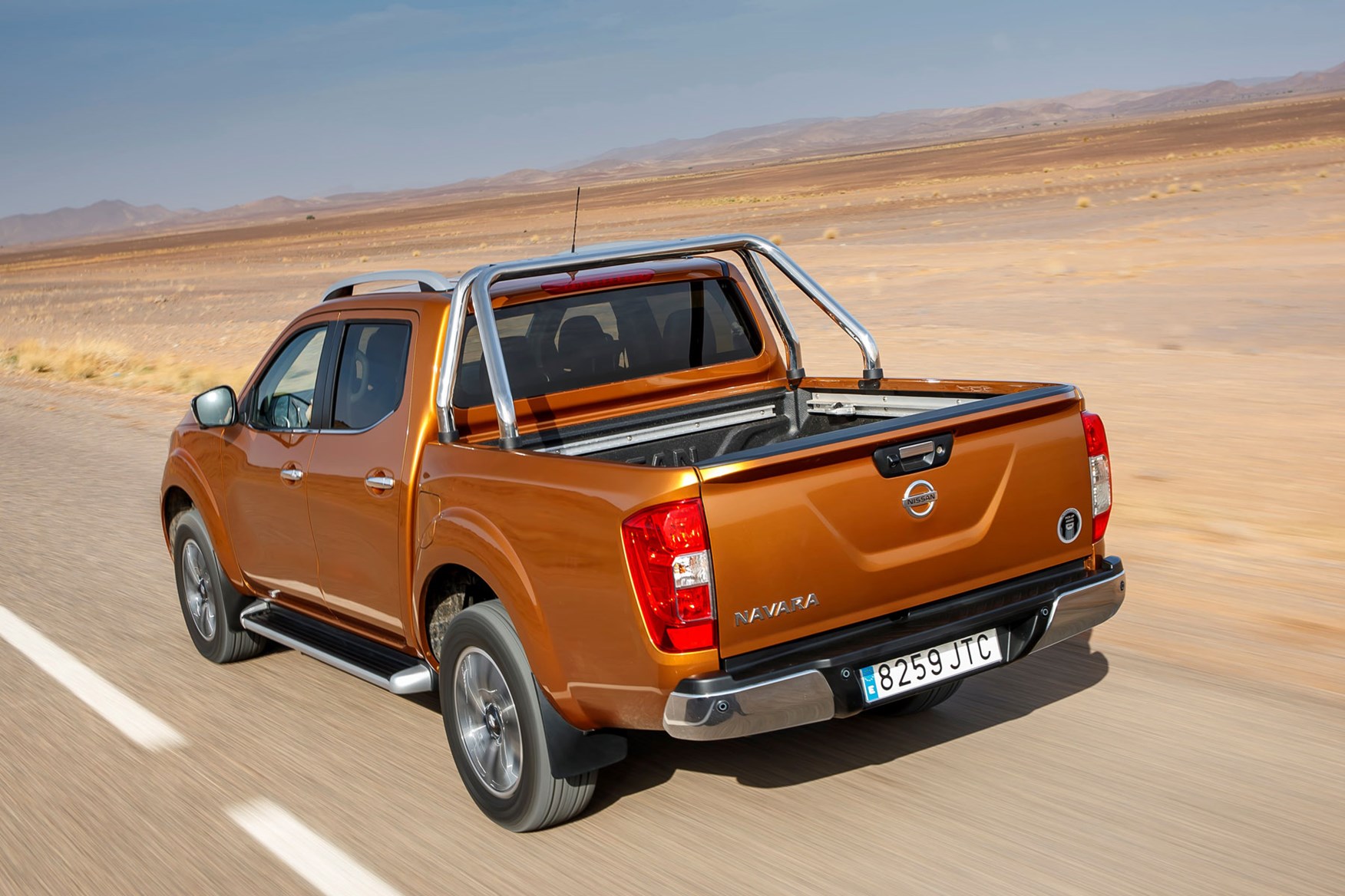 Nissan Navara Tekna review - rear view, driving on road, orange