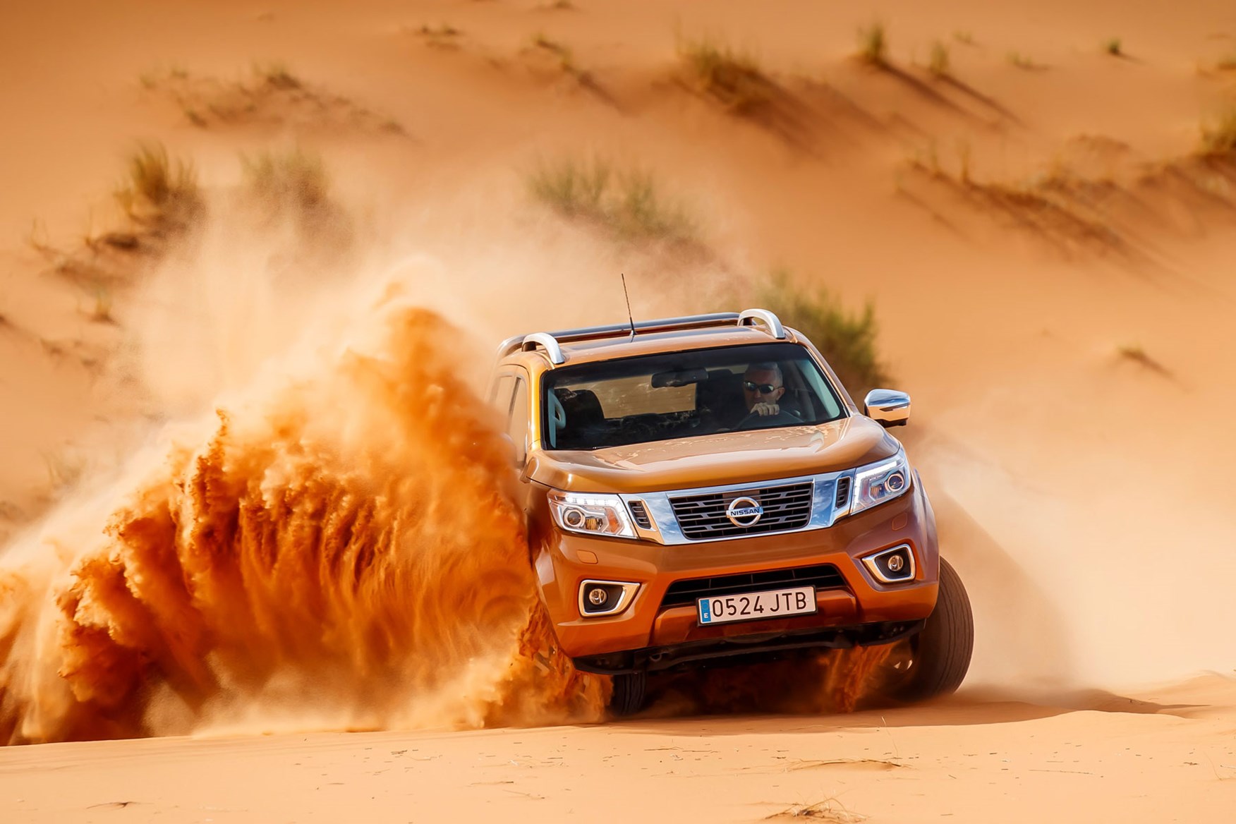 Nissan Navara Tekna review - driving in the Sahara Desert, front view, orange, spraying sand