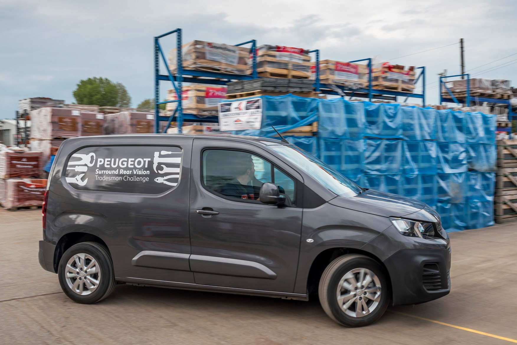 Peugeot Partner review 2020, side view, grey, driving round builders' yard