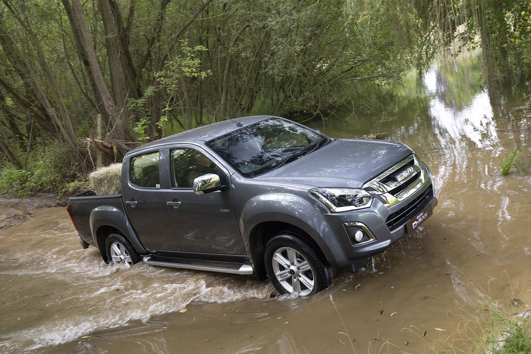 Isuzu D-Max off-road - splashing through river with hay bale in load area