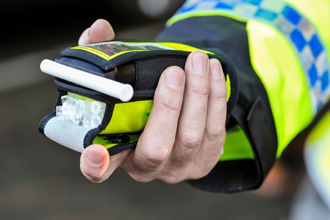 When can I drive after drinking?: a police officer holding a breathalyser