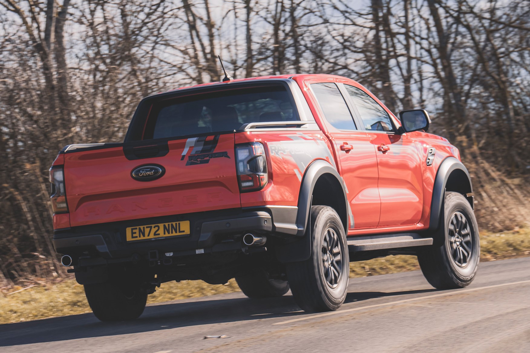 Ford Ranger Raptor (2023) review: rear three quarter cornering, orange paint, country road