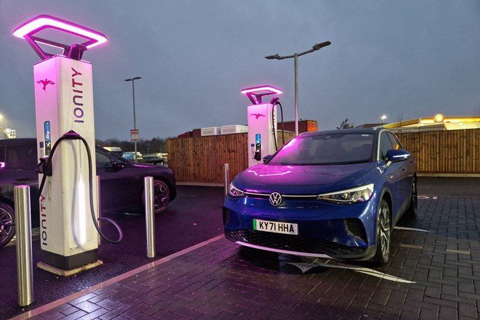 Volkswagen ID.4 long-term test - front view, blue, charging at Cambridge Services at night