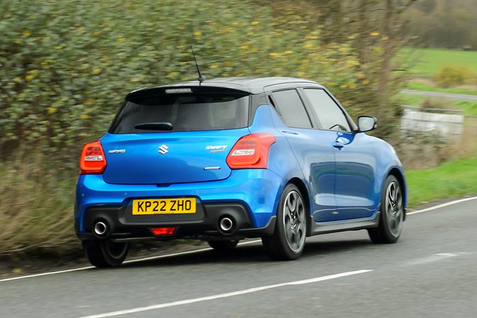 Suzuki Swift Sport (2023) review: rear three quarter driving, blue car, British B-road