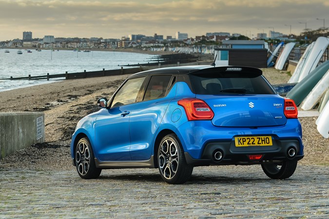 Suzuki Swift Sport (2023) review: rear three quarter static, blue car, beach background