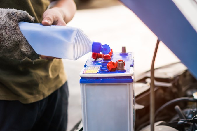 Mechanic topping car battery up with de-ionised water