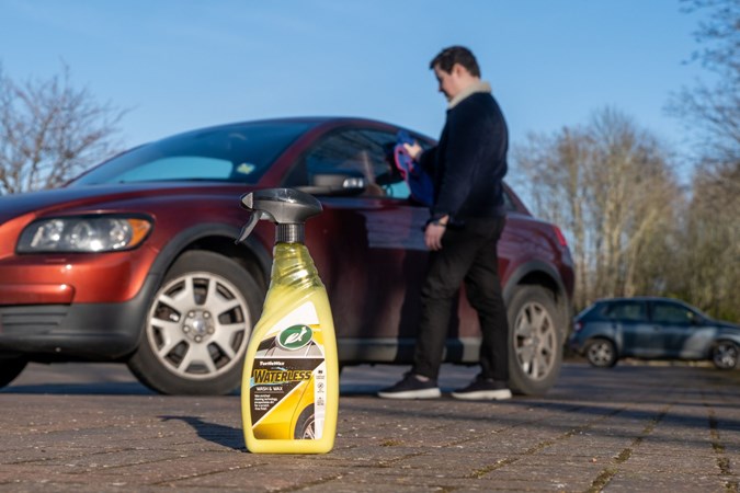 The bottle of Turtle Wax Waterless next to a car being cleaned