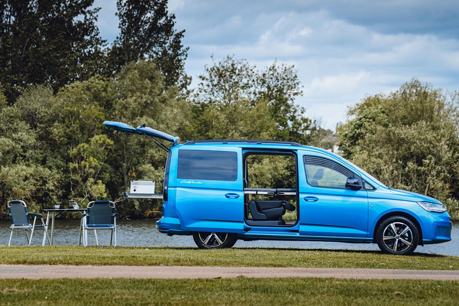 Volkswagen Caddy California campervan, side view, blue, with doors open, table, chairs, bed