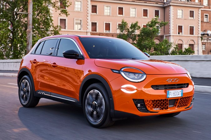 Fiat 600e front three quarter driving, orange paint, dusk