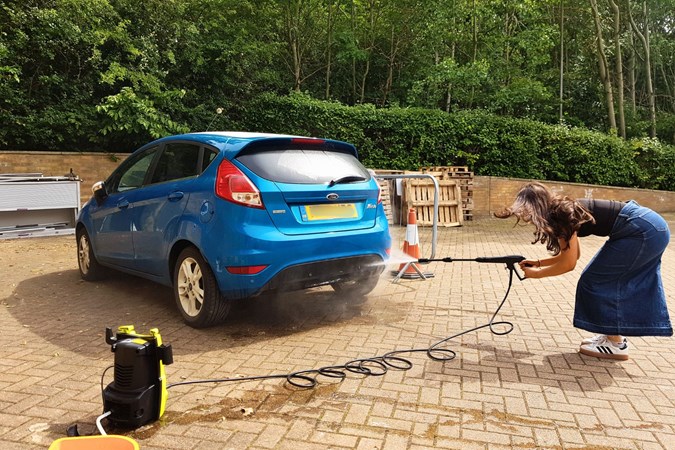 Paula Cullington tests a pressure washer on a blue car.