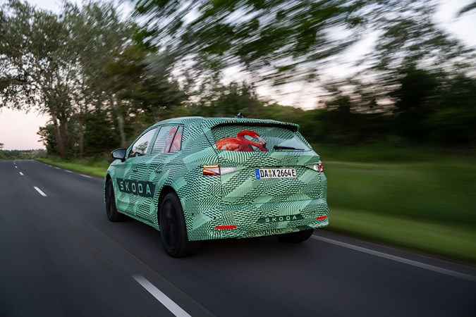 Skoda Elroq prototype: rear three quarter driving, on a country road, green camo wrap