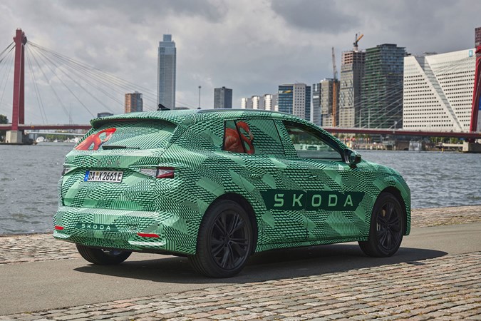 Skoda Elroq prototype: rear three quarter static, green camo wrap, city in background