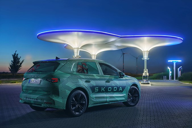 Skoda Elroq prototype: front three quarter static, green camo wrap, futuristic charging point in background