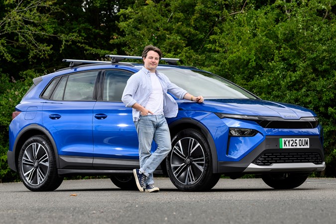 Ryan Gilmore stands next to a blue Skoda Elroq, front three quarters