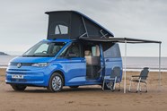 Image of a blue Volkswagen California at the beach with its pop-top up | Parkers cars