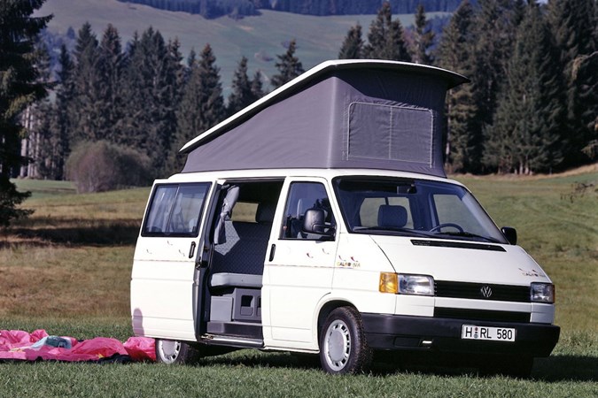 Image of Volkswagen T4 camper van in white, front right three-quarters view with raised pop-top and side door open