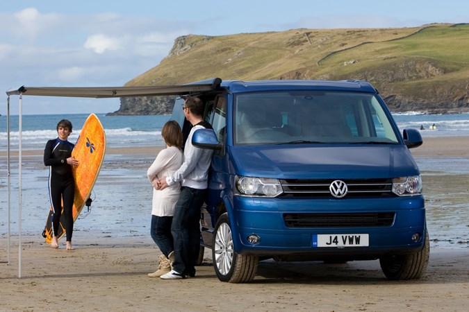 Image of the Volkswagen T5.1 California, in blue, with awning set-up, viewed from the front