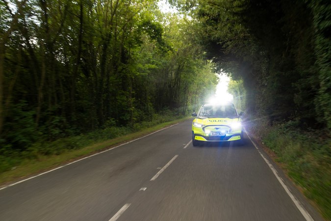 Image of a Ford Mustang Mach E police car driving with lights flashing