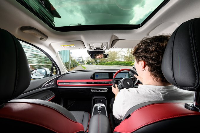 Ryan Gilmore drives the GWM Ora 03, interior shot, black, red, driving | Parkers