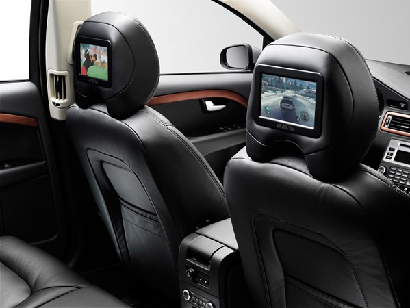 The interior of a premium vehicle from the rear seats, with display screens in-build to the front seat head rests, showing golf and video game respectively
