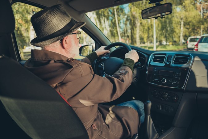 Image of a man wearing a trilby hat while driving