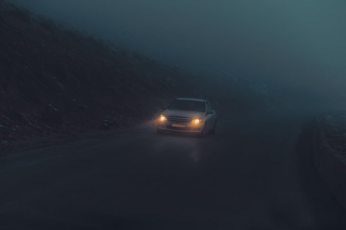 Image of a dimly lit Mercedes C-Class driving through fog