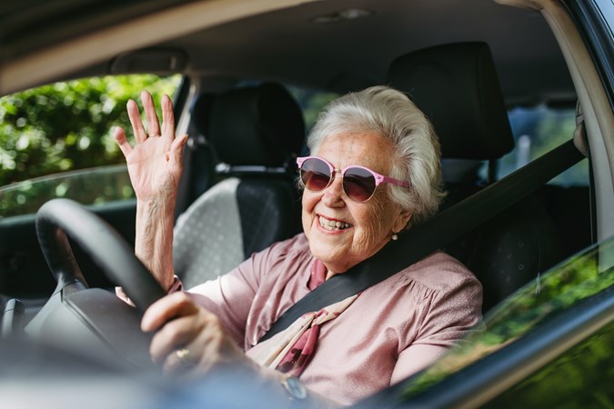 Image of a happy elderly woman behind a car's steering wheel