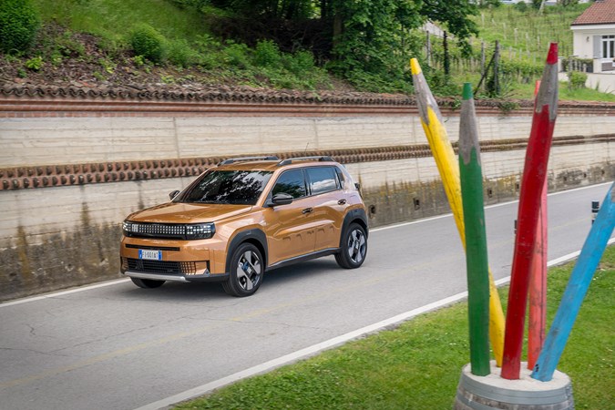 Fiat Grande Panda Hybrid (2025) review: front three quarter driving, bronze paint, giant pencils in foreground