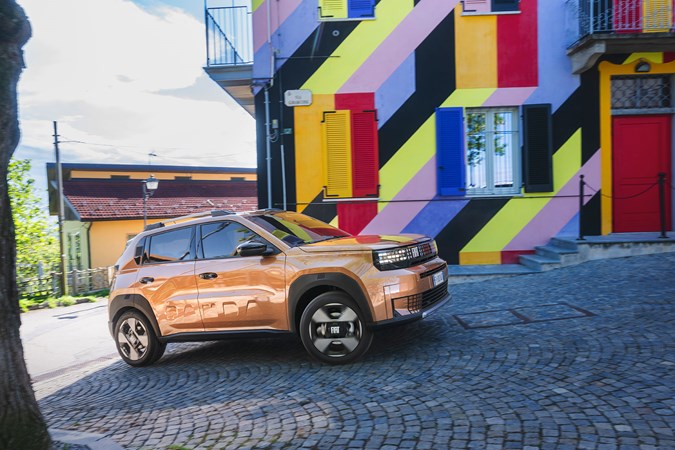 Fiat Grande Panda Hybrid (2025) review: front three quarter cornering, bronze paint, colourful house in background