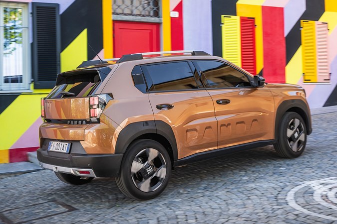 Fiat Grande Panda Hybrid (2025) review: rear three quarter cornering, bronze paint, colourful house in background