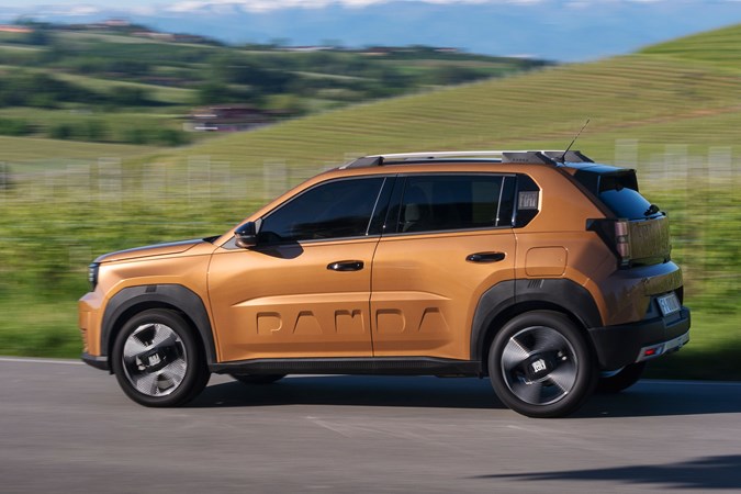 Fiat Grande Panda Hybrid (2025) review: side view driving, bronze paint, hills in background
