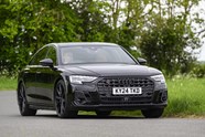 Image of a black Audi S8 driving around a corner, looking at its front right corner
