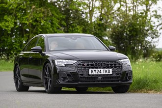 Image of a black Audi S8 driving around a corner, looking at its front right corner